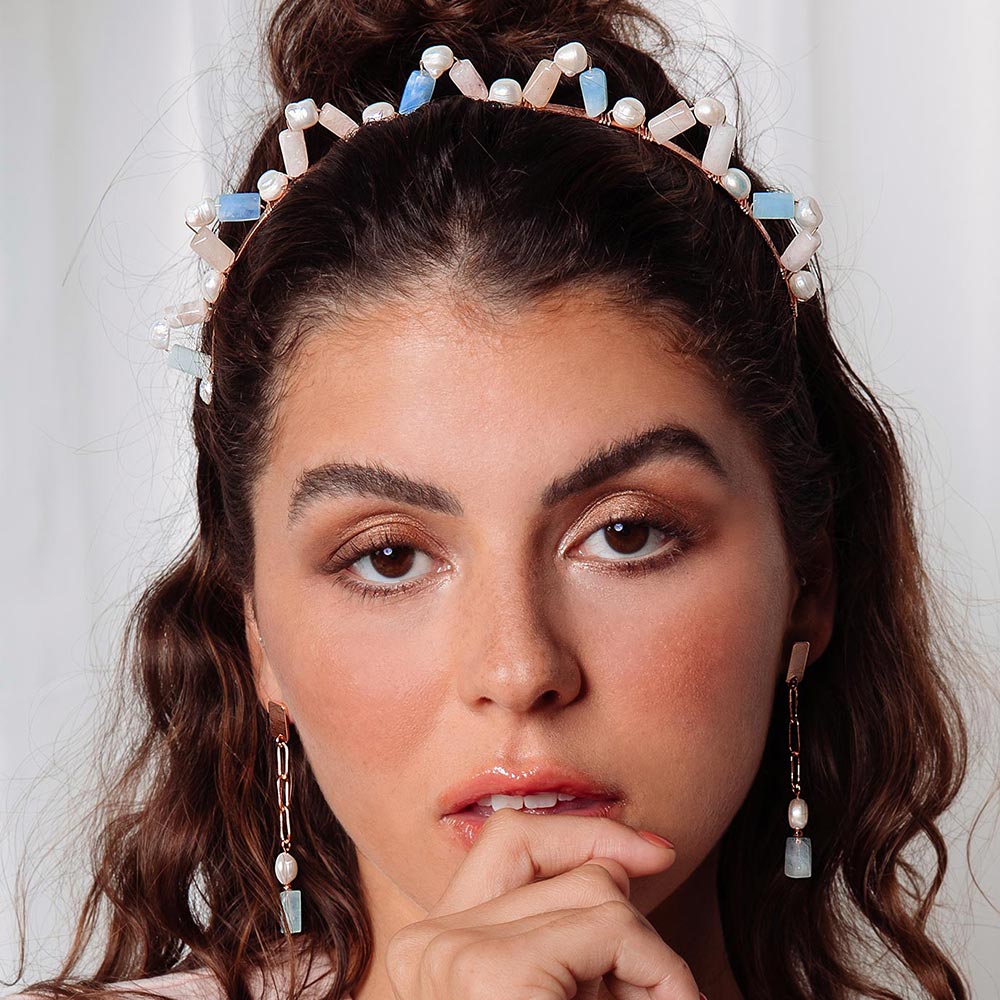 Aimee natural multi-stone crown headband with hand under chin.