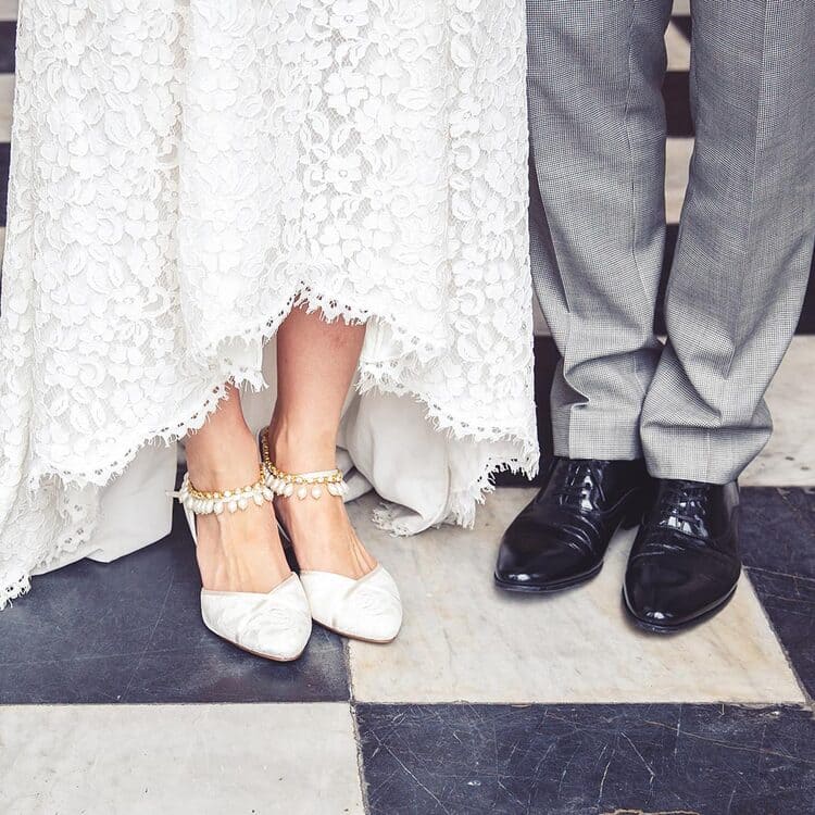 Katie and Nick legs on black and white checkered floor. Katie wears gold crystal Khaleesi anklets with white heels and dress