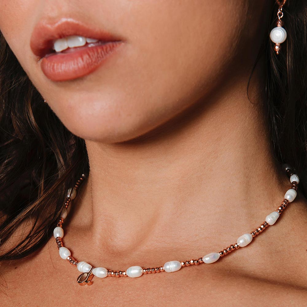 Tarni personalised rose gold and pearl inital necklace with d initial close up of neck.