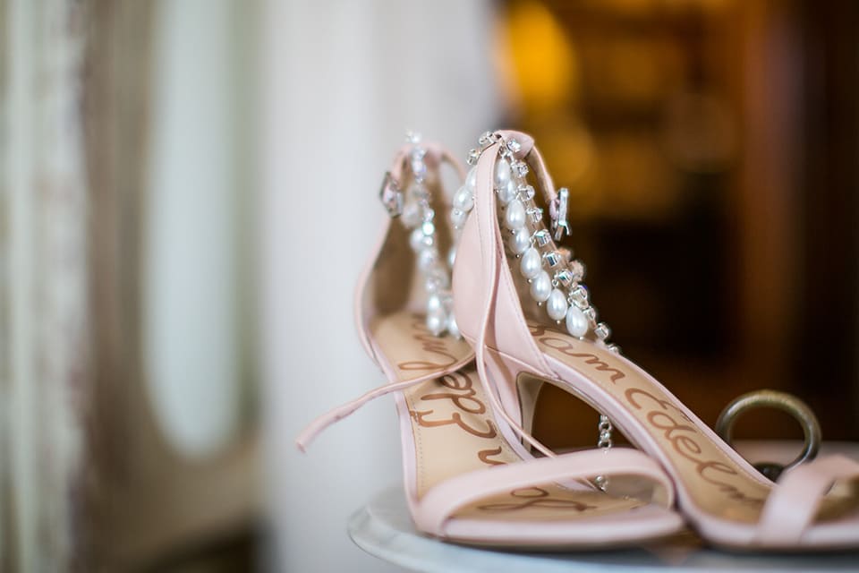 A pair of customised silver Khaleesi anklets in the foreground resting on a pair of wedding heels