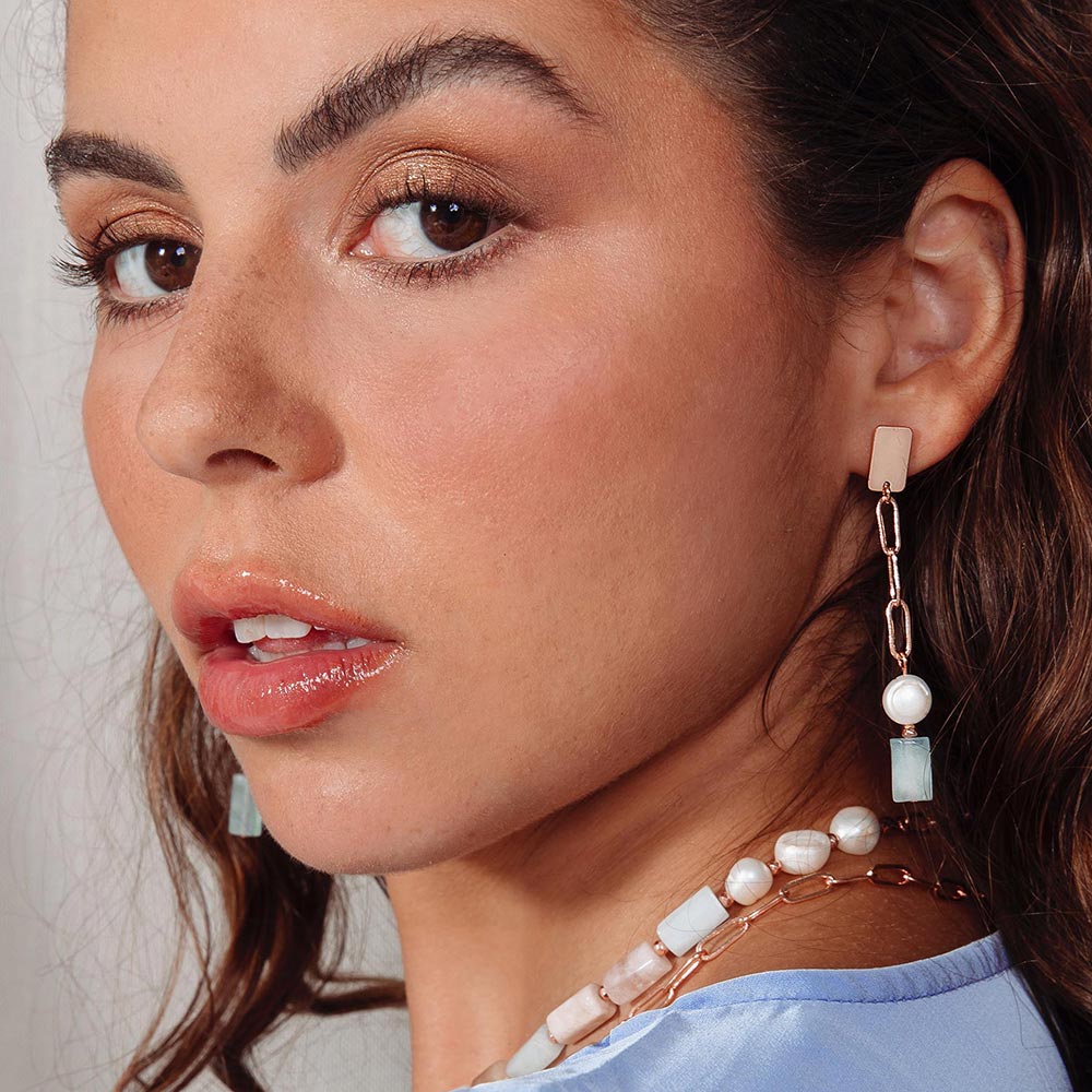 Aimee freshwater pearl and morganite stone earrings on left ear looking over shoulder.