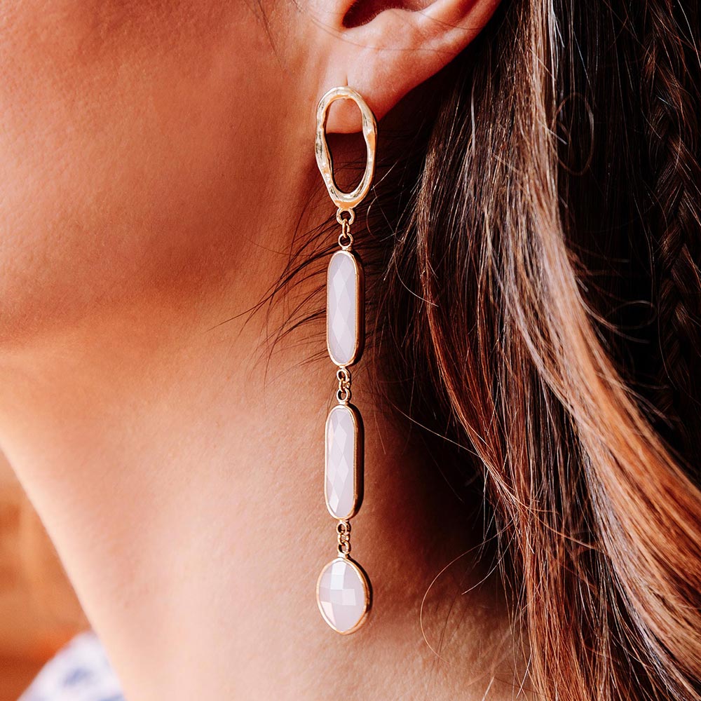 Azaria long white crystal gold earrings close up left ear