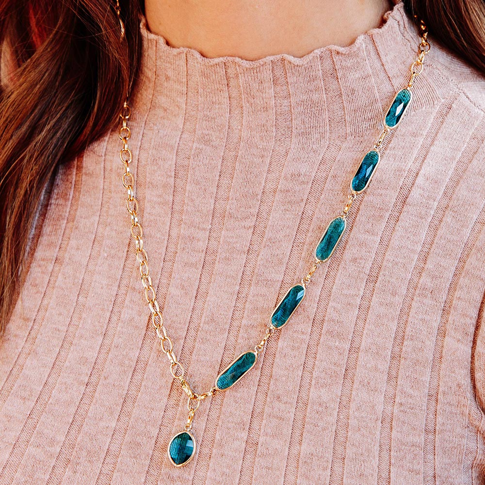 Azaria multiway necklace teal crystal long gold chain necklace close up with beige knit top