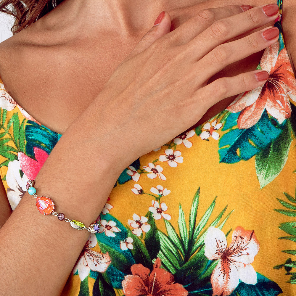Fred colourful mix crystal bracelet on right arm worn with tropical dress.