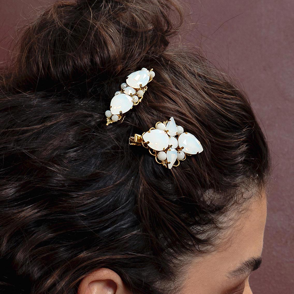 Imogen white opal gold wedding hair clips worn on right side with loose curls and top bun.