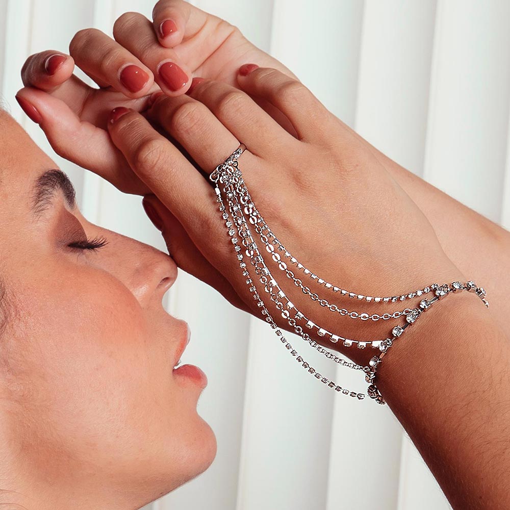 Keisha rhinestone hand chain bracelet on right hand raised up.