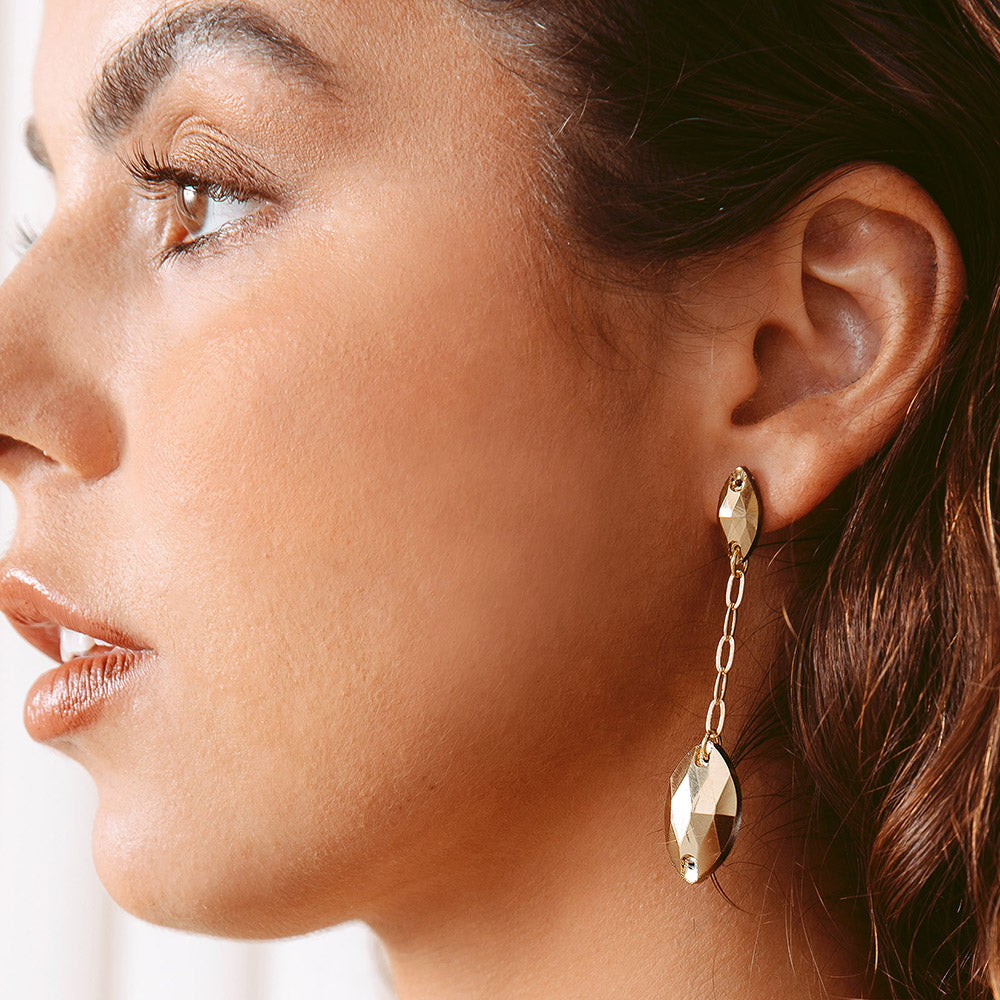 Kyra gold crystal and chain drop earrings close up on left ear