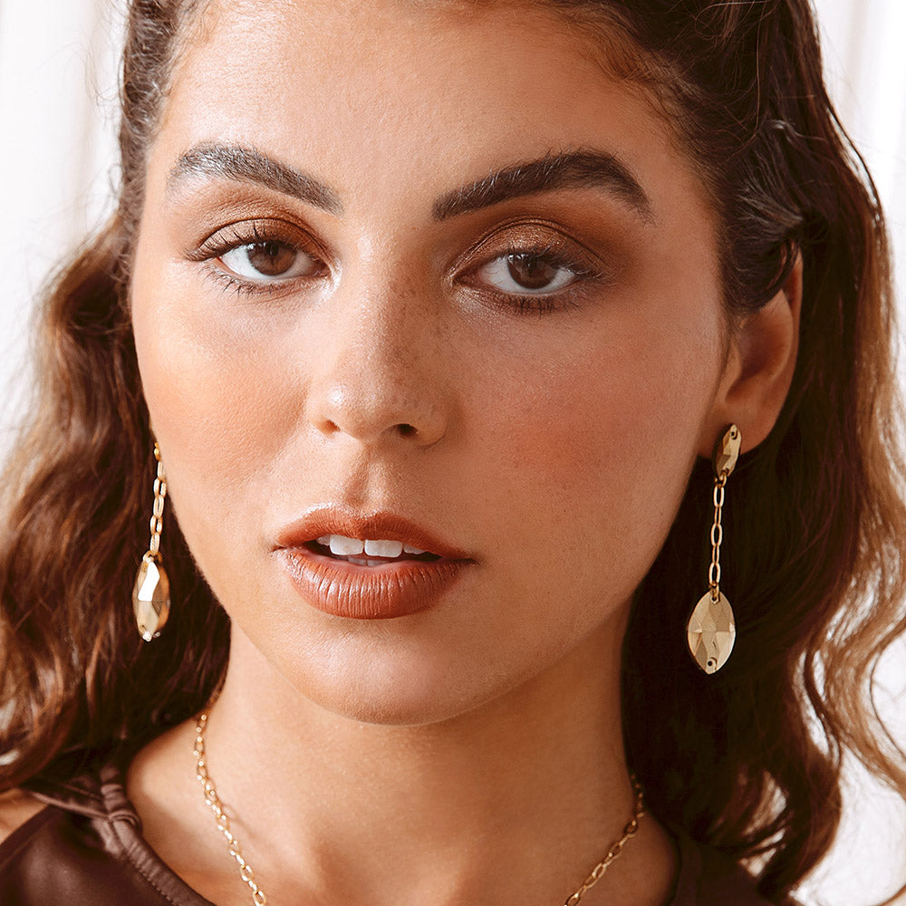Close up of woman wearing Kyra gold crystal and chain drop earrings