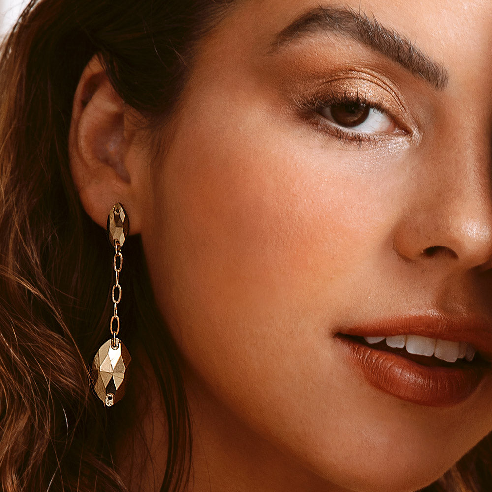 Kyra gold crystal navette and chain drop earrings close up on right ear