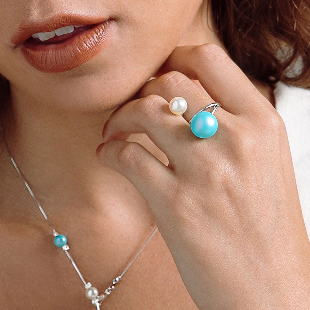 Close-up of a woman's hand wearing a turquoise and pearl ring, with a matching necklace.