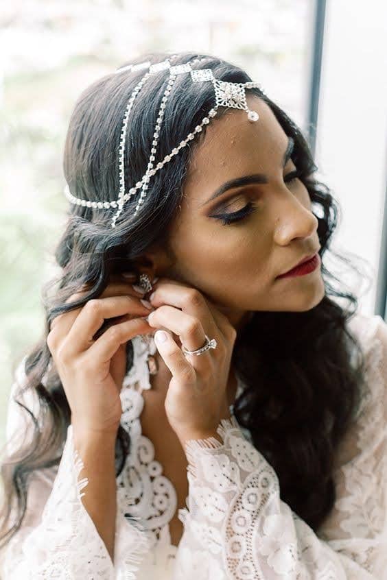 Bride Raysa adjusts earring with lace dress and wearing custom headpiece