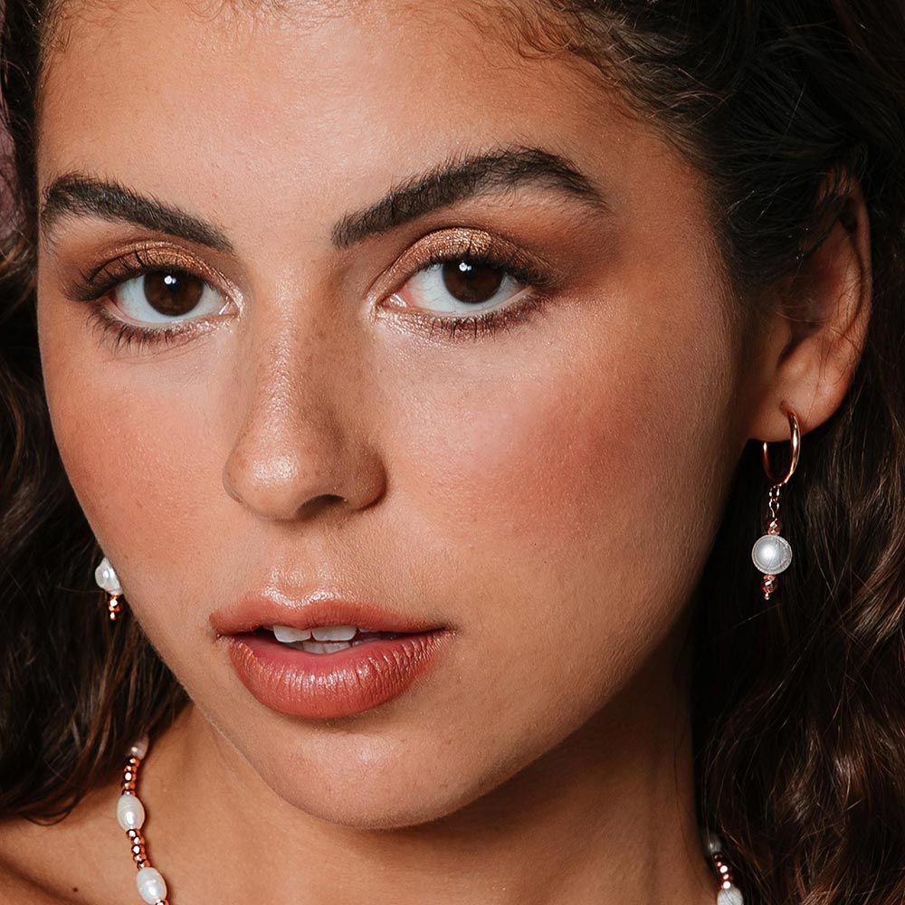 Tarni freshwater pearl rose gold hoop earrings pair focus on left ear.
