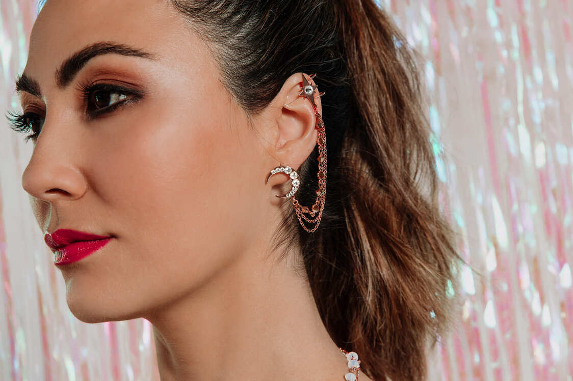 Callista moon and star ear cuff on left ear with iridescent streamer wall background