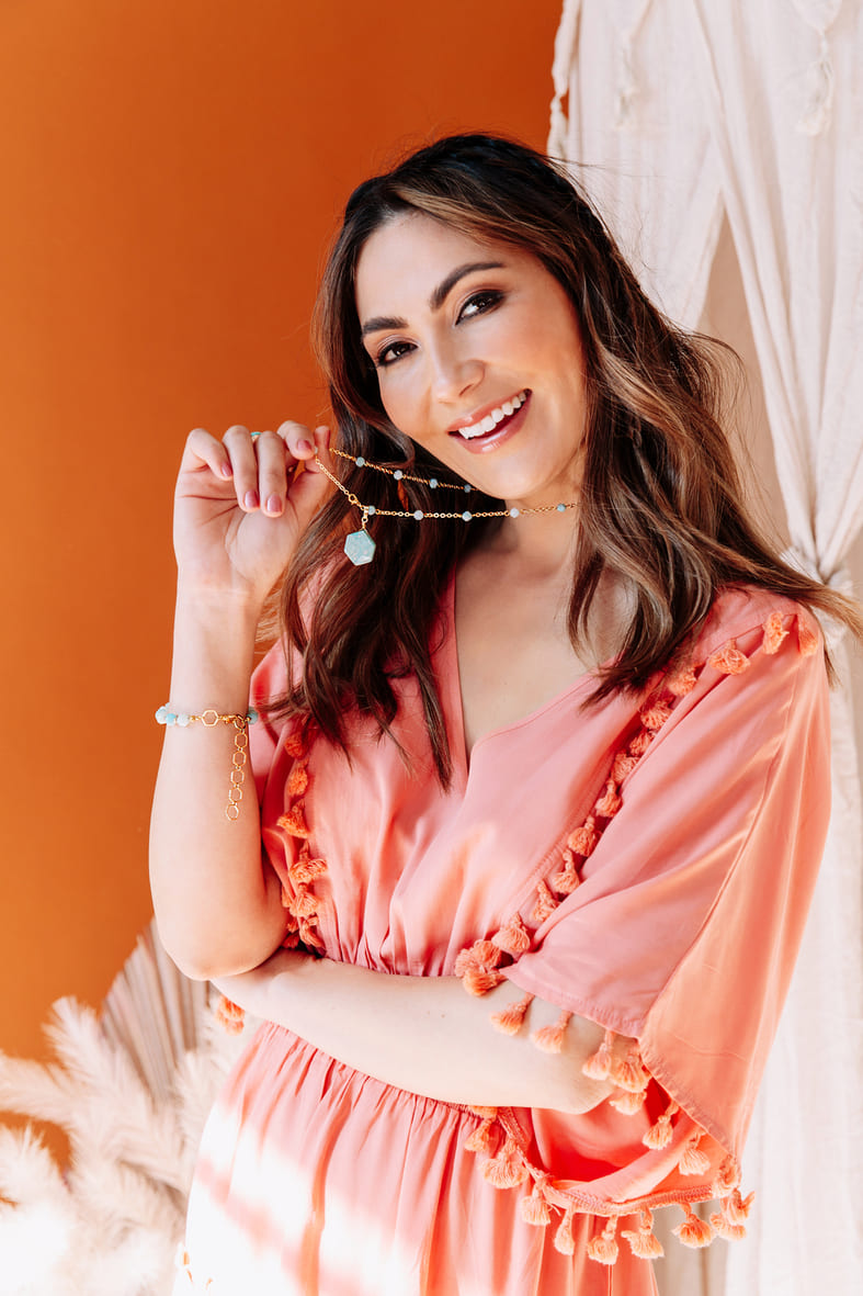 Coral dress smiling holding Kiana hexagon stone necklace