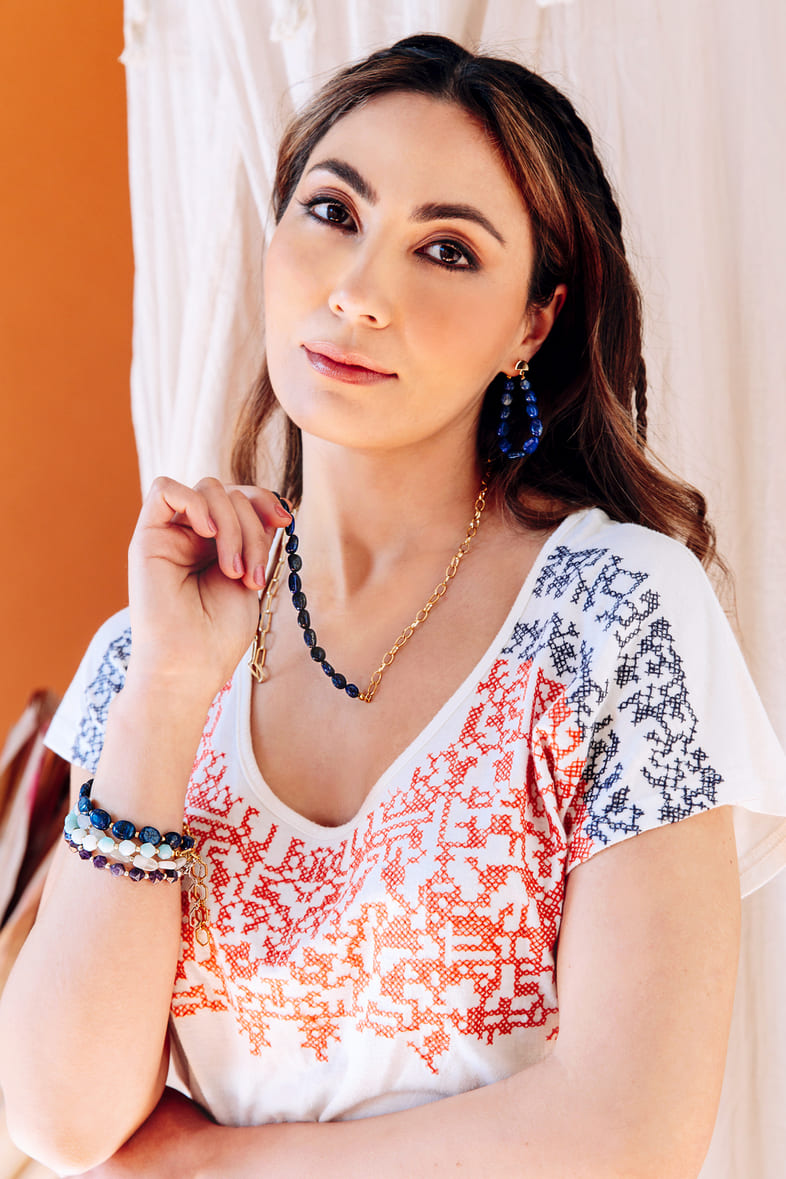 Casual white top holding blue Neomi stone necklace and earrings