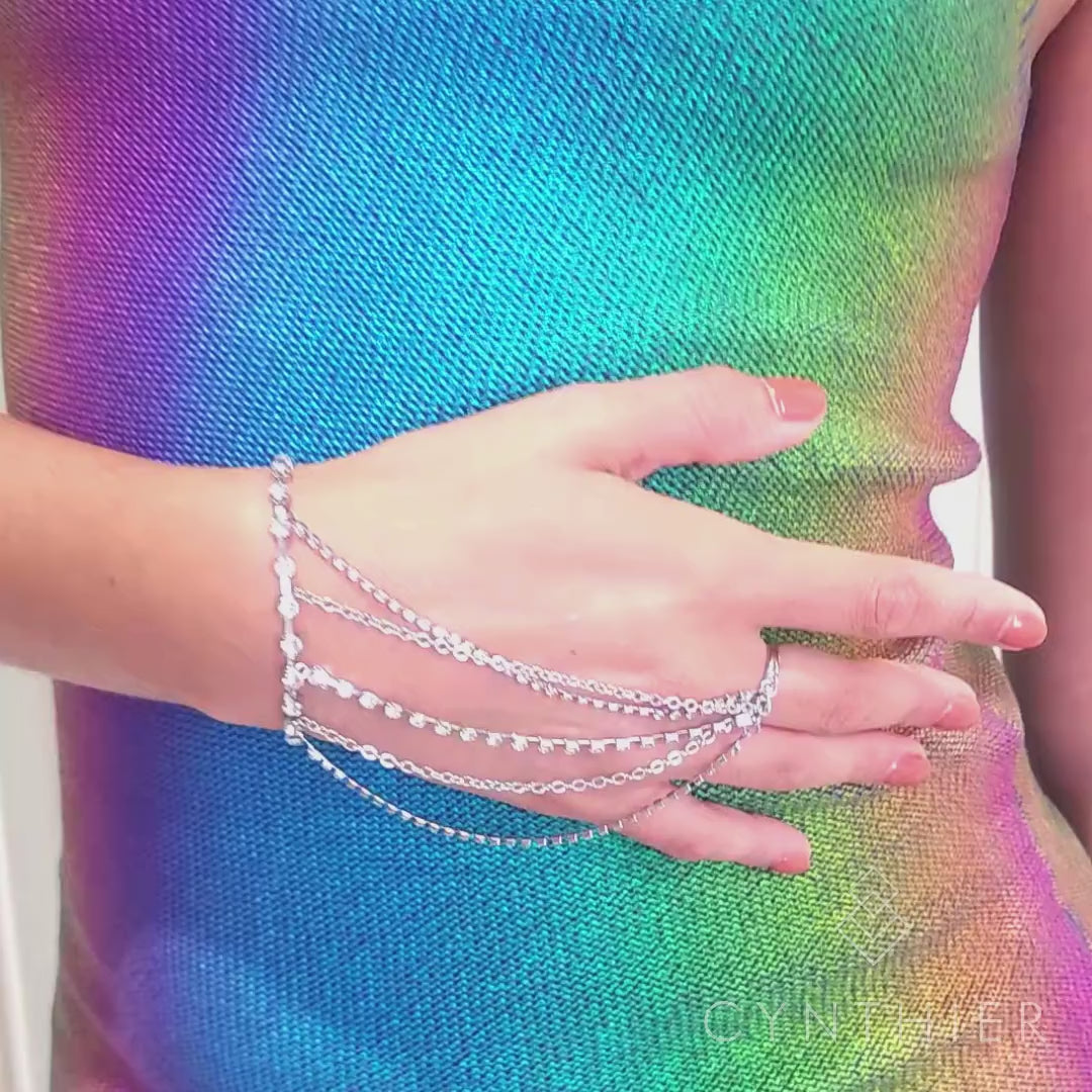 Keisha rhinestone hand chain bracelet on right hand at waist, hand goes up to face.