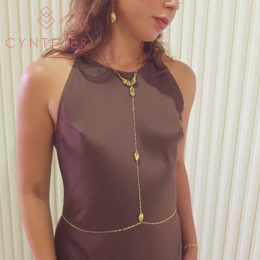 Woman wearing Kyra body chain necklace with brown dress, moving body from left to right.