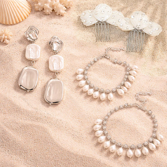 Pearl jewelry set including earrings and bracelets on a sandy surface with seashells.
