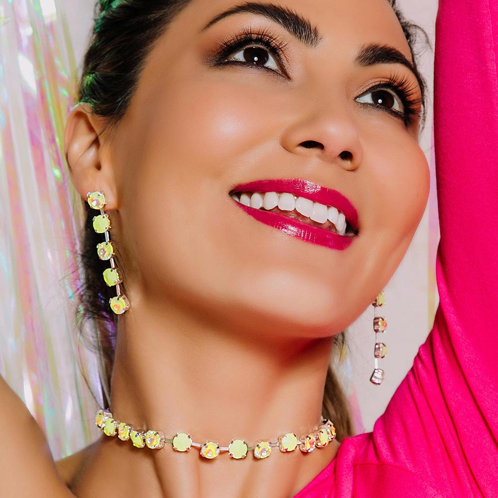 Daiquiri neon crystal necklace and neon yellow earrings, model smiling with arms up