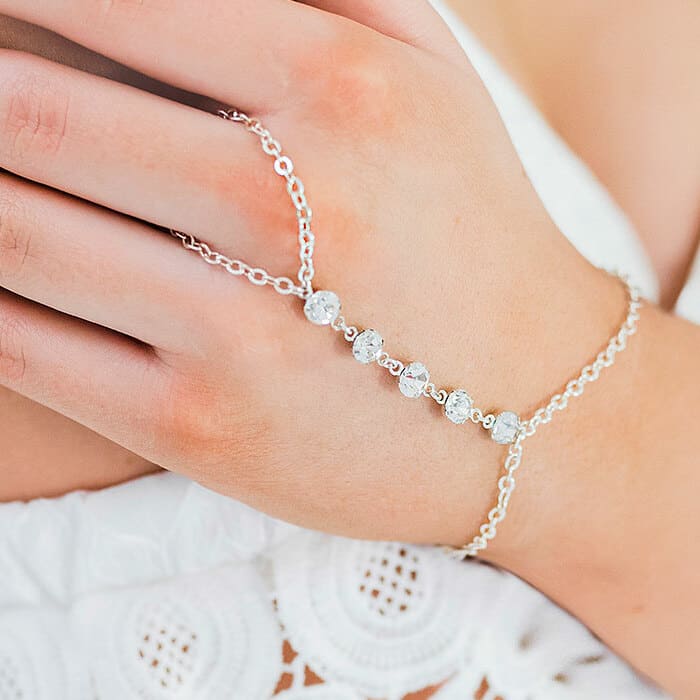 Alek crystal hand chain bracelet in silver on left hand holding shoulder