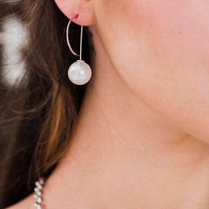Close up of Affordable Pearl Threader Romee Earrings in silver worn on right ear