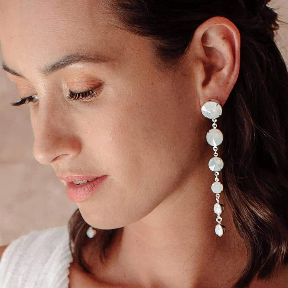 Kelsey Crystal Drop Earrings in White opal close up on left ear